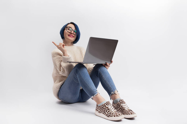 A woman sitting on the floor and holding a laptop. Isolated - Фото, изображение