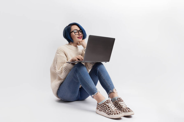 A woman sitting on the floor and holding a laptop. Isolated - Foto, imagen