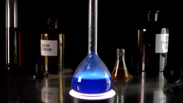 Reazione chimica in un pallone con un liquido blu. Reagenti chimici hanno interagito producendo fumo bianco. - Filmati, video
