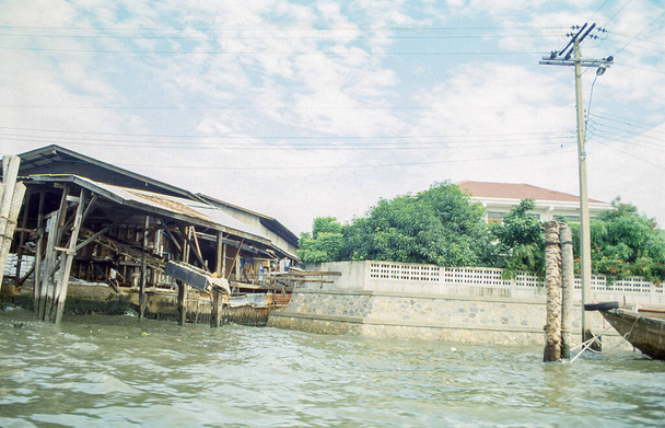 A slum poor people's construciton next to a luxurious villa in Bangkok, Thailand. Retro 1993 capture on film demonstrating social inequality. - Photo, Image