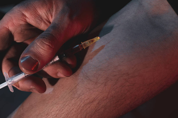 Man taking drugs on dark background, closeup - Фото, зображення