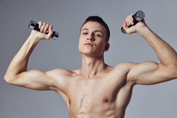 спортивний чоловік з гантелями в руках тренує силу м'язів
 - Фото, зображення