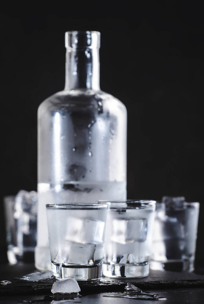 Cold Vodka in shot glasses on black background, ready to drink  - Fotó, kép