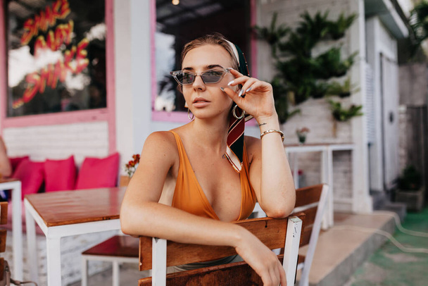 Outside portrait of pretty woman in sunglasses resting outside. Outdoor portrait of elegant woman drinking tea in restaurant on the street. High quality photo - Photo, Image