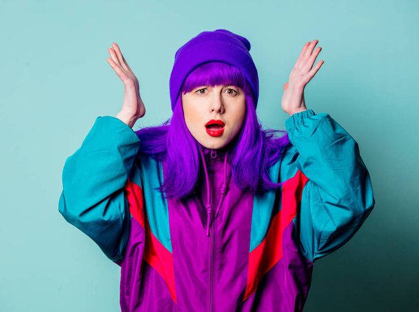 Sorpresa ragazza bianca con capelli viola e tuta anni '80 su sfondo blu - Foto, immagini