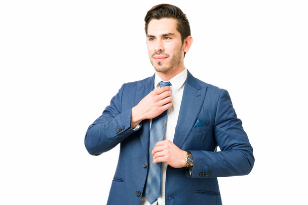 Meşgul genç avukat kravatını düzeltiyor. Başarılı bir iş adamı takım elbise giyiyor ve mesleğiyle gurur duyuyor. - Fotoğraf, Görsel
