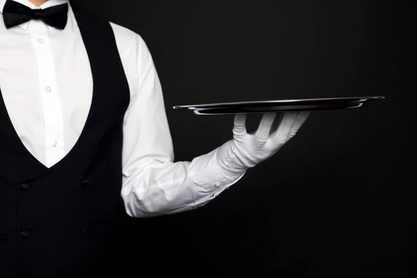 Butler with tray on black background, closeup - Valokuva, kuva