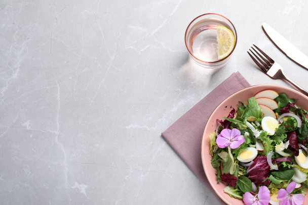 Fresh spring salad with flowers served on grey table, flat lay. Space for text - Zdjęcie, obraz