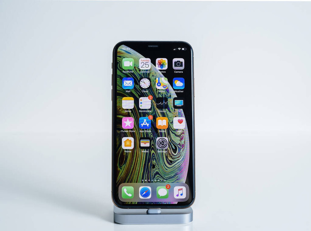 Elszigetelt fehér legújabb Apple Computers Iphone Smartphone XS MAx telefon minden kezdőképernyős alkalmazások töltés dokkoló állomás - Fotó, kép