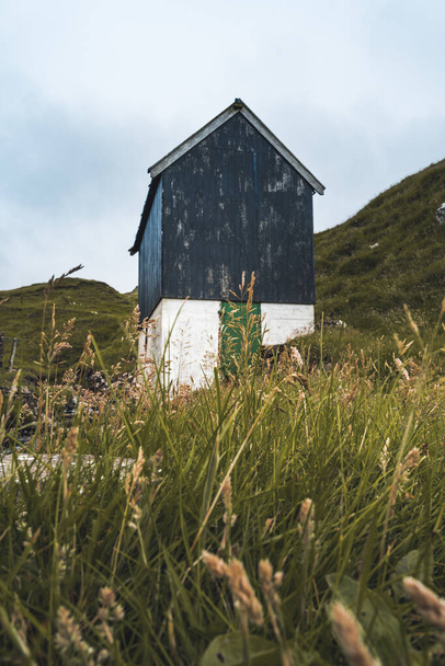 Bour village Grass-covered picturesque houses at the Faroese coastline in the village Bour with view onto Dranganir and Tindholmur during spring. - 写真・画像