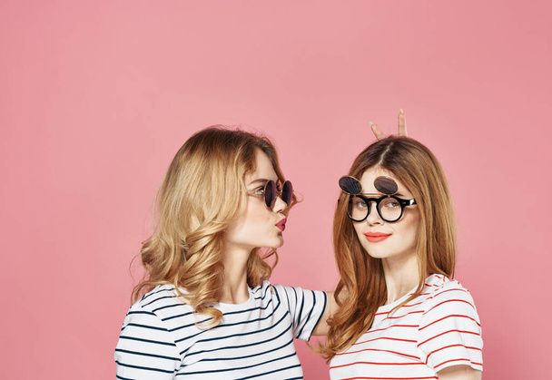 Mulheres em camisetas listradas usando óculos de sol estúdio de moda fundo rosa - Foto, Imagem