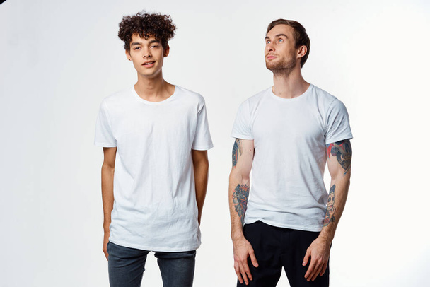 Dos amigos alegres en camisetas emociones estilo de vida fondo claro - Foto, imagen