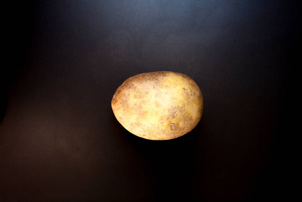 Potato on black table, food background. Isolated potato - Fotó, kép