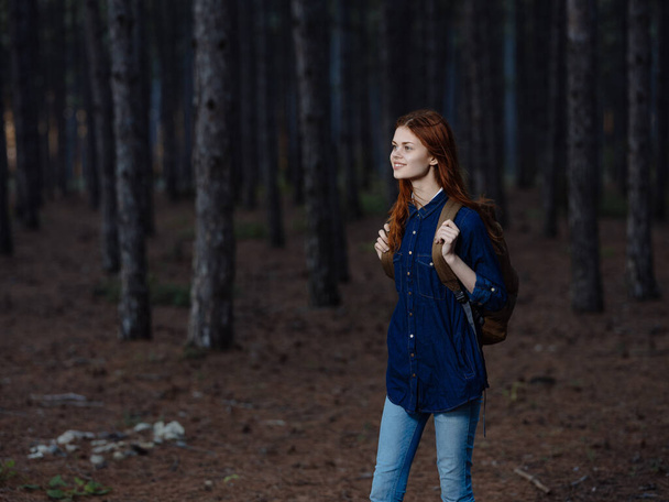 Женщина-туристка с рюкзаком на спине гуляет по природе в лесу - Фото, изображение