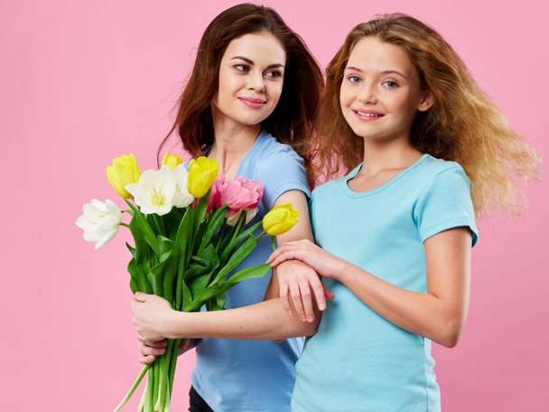 少女はピンクの背景に春の花の花束を母親に与えました - 写真・画像
