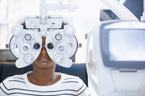 Young woman african american eye exam with diagnostic ophthalmology in optical clinic. professional ophthalmic checking vision of patient. phoropter machine, Eye health check and ophthalmology concept. - Photo, Image