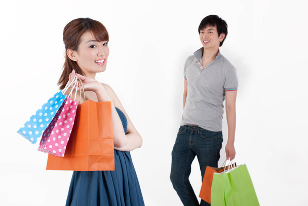 白い背景にショッピングバッグを持つ幸せなカップル - 写真・画像