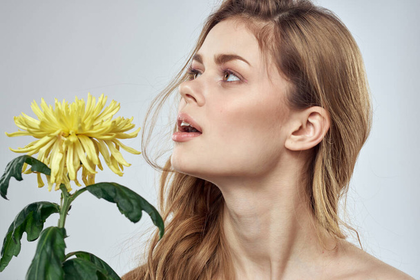 Портрет красивой женщины с желтым цветком на светлом фоне - Фото, изображение