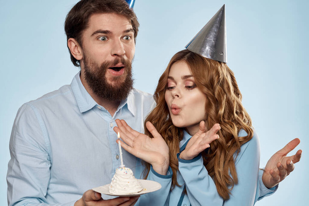 Allegro uomo e donna con torta in un piatto partito aziendale sfondo blu - Foto, immagini