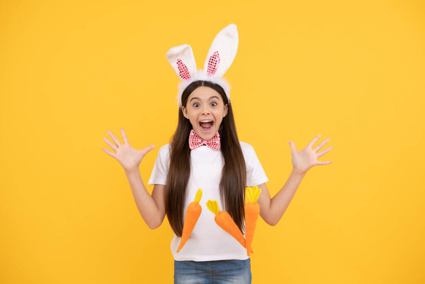 здивована великодня дитина дівчина в вухах кролика і краватка тримає моркву, щасливий Великдень
. - Фото, зображення