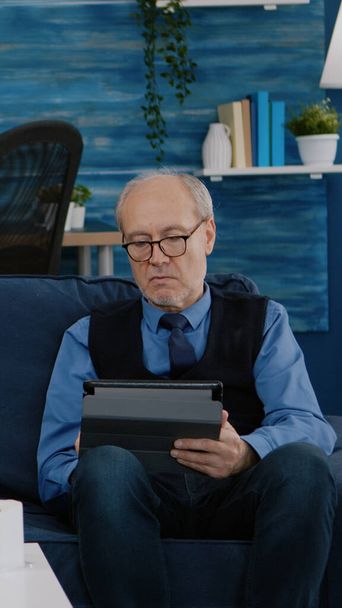 Starší muž zkouší na tabletu, zatímco jeho žena používá notebook - Fotografie, Obrázek