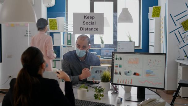 Група бізнес-партнерів з масками для обличчя, що аналізують графіки за допомогою цифрового планшета
 - Фото, зображення
