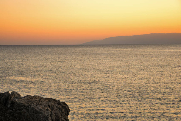 Sunset on the sea against the backdrop of low mountains - Photo, Image