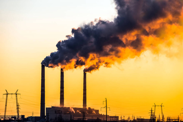 Zonsondergang boven de industriële stad.Fabrieksschoorstenen rook.Milieuprobleem van milieu- en luchtvervuiling.Klimaatverandering, milieuramp. De lucht is rokerig met giftige stoffen - Foto, afbeelding