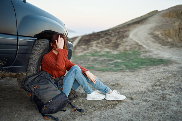 женщина турист в горах на природе сидит рядом с автомобилем и горы дорожный пейзаж - Фото, изображение