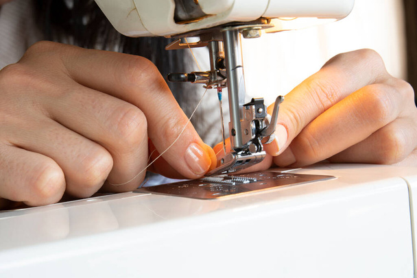 young woman putting thread on needle of sewing machine - Foto, Imagem