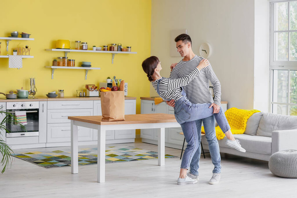 Happy young couple dancing in kitchen - Фото, изображение