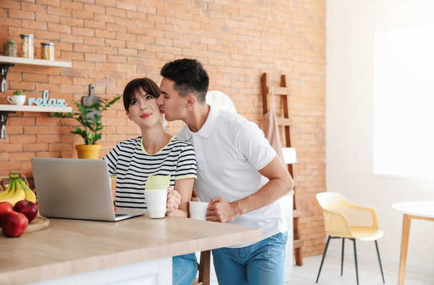 Morning of happy young couple with laptop in kitchen - Φωτογραφία, εικόνα
