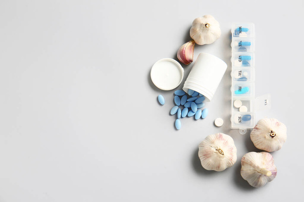 Frisse knoflook met pillen op lichte achtergrond - Foto, afbeelding