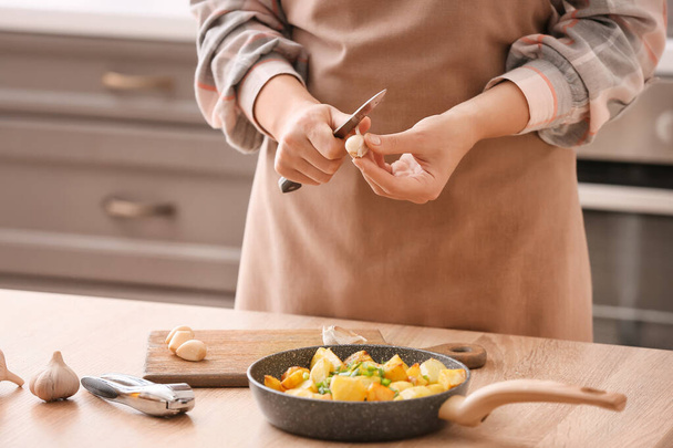 Mujer pelando ajo en la mesa en la cocina - Foto, imagen
