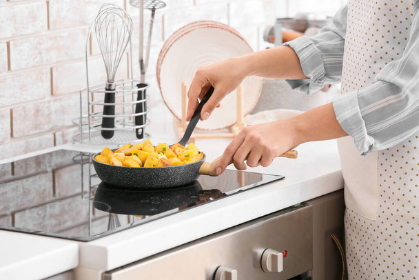 Woman cooking potato with garlic in kitchen - Fotografie, Obrázek