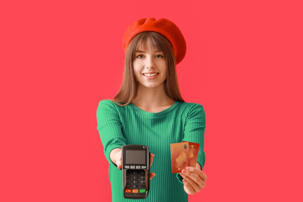 Giovane donna con terminale di pagamento e carte di credito su sfondo a colori - Foto, immagini