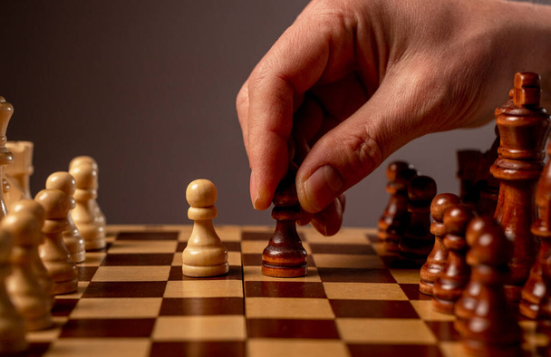 Male hand moving pawn on chess board, starting game. Making business decision concept - 写真・画像