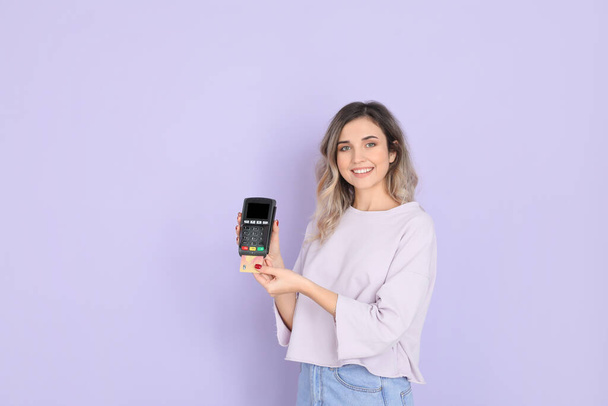 Young woman with payment terminal on color background - Photo, Image