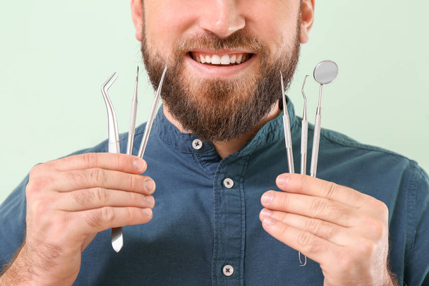 Young man with dental tools on color background, closeup - Photo, Image