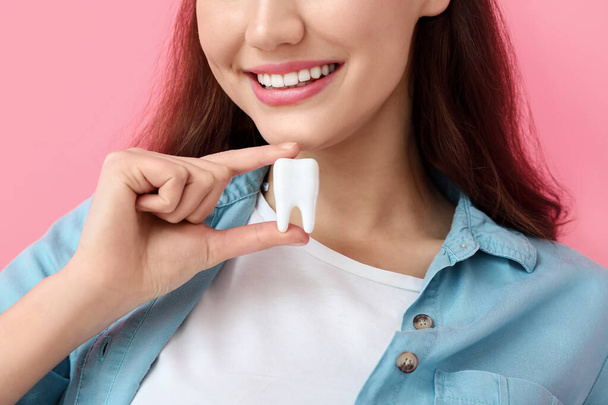 Beautiful young woman with plastic tooth on color background, closeup - Fotografie, Obrázek