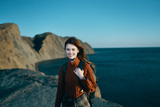 χαρούμενη γυναίκα με σακίδιο στη φύση βραχώδη βουνά ορίζοντα της ελευθερίας του ωκεανού - Φωτογραφία, εικόνα