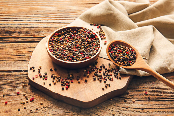 Bowl and spoon with mixed peppercorns on wooden background - Foto, Bild