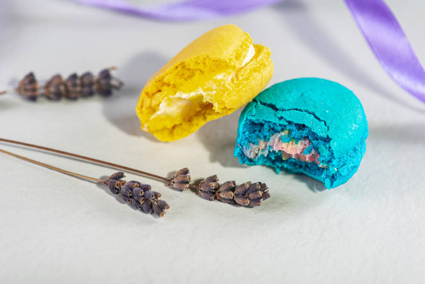 hallitsemattomasti purettu makea, maukas ja värillinen sininen ja keltainen ranskalainen makaroni kevyellä taustalla. Jälkiruoka on makeaa. Valikoiva keskittyminen. Makea käsite - Valokuva, kuva