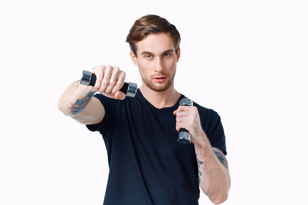 guy athlete in a black t-shirt with dumbbells in his hands on a white background - Photo, Image