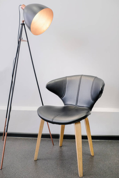 Vloerlamp met zwarte fauteuil. Interieur studio voor een fotoshoot, video bloggen. Het concept van de directeur. Minimalistisch interieur. - Foto, afbeelding