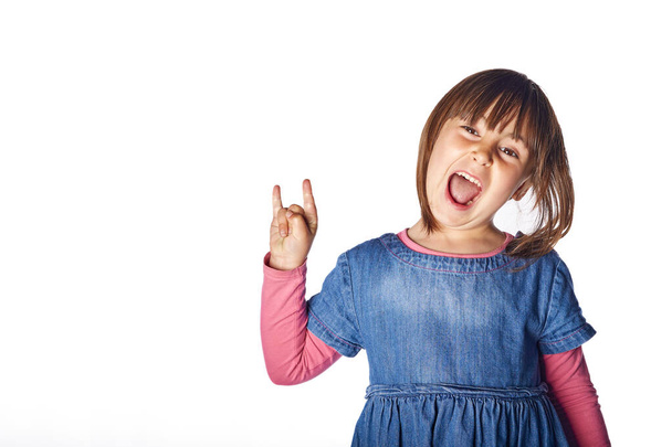 Kleines Mädchen zeigt Rock and Roll Handzeichen isoliert auf weißem Hintergrund. Zeichen der Hörner. sich cool fühlen - Foto, Bild