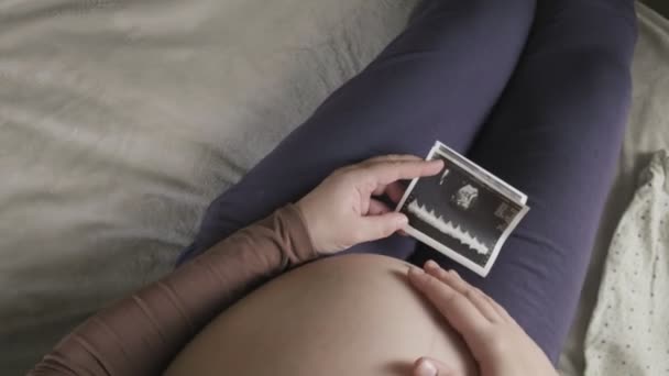 verwacht zwangere vrouw met een grote buik kijken naar echografie scan thuis - Video