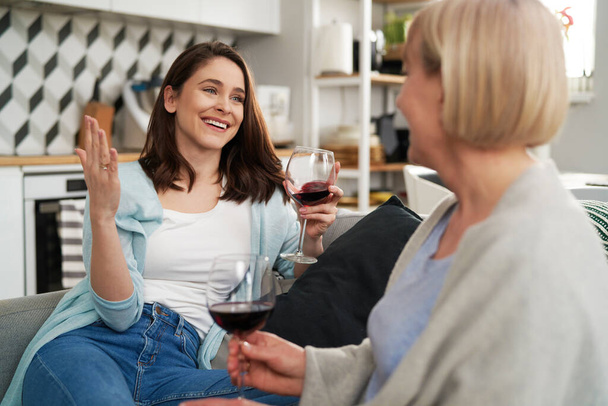 Два поколения женщин проводят время, выпивая вино дома                                - Фото, изображение