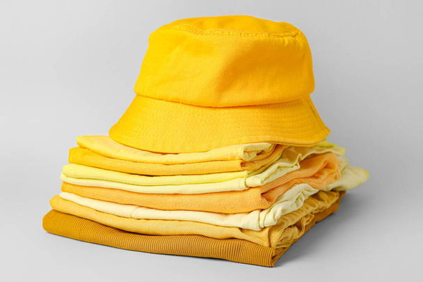 Stack of stylish clothes with hat on grey background - Photo, Image