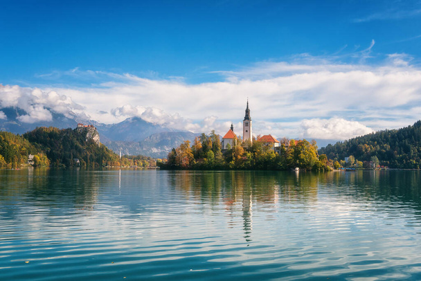 Famous alpine Bled lake (Blejsko jezero) in Slovenia, amazing autumn landscape. Scenic view of the lake, island with church, Bled castle, mountains and blue sky with clouds, outdoor travel background - Photo, Image